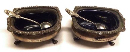 A pair of George V Four Footed Salts, of typical form fitted with blue glass liners and gadrooned