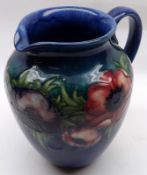 A Moorcroft Anemone pattern Jug, decorated with coloured flowers on a blue background, bears