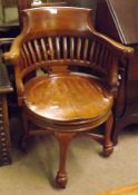 An early 20th Century Oak Swivelling Desk Chair, heavy shaped back over slatted support and circular