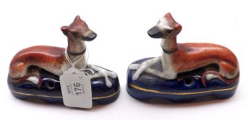 A pair of small Staffordshire Inkwells, modelled as recumbent greyhounds on blue plinth bases,