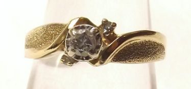 A yellow metal Ring marked 10K set with central Diamond and two small stones surrounding