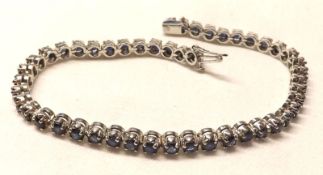 A precious metal Line or Tennis Bracelet, set with forty-eight Dark Blue Sapphires, stamped “9K”,