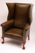 A late 19th Century Leather Upholstered Porters type Wing Armchair, raised on front ball and claw