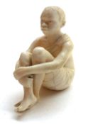 A Carved Ivory Figure modelled as a seated African tribal boy, signed, 2” high