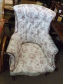 A late Victorian Armchair, upholstered in buttoned floral fabric, raised on front turned legs and