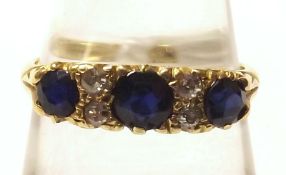 A hallmarked 18ct Gold three Dark Blue Sapphire and four small Old Cut Diamond Ring