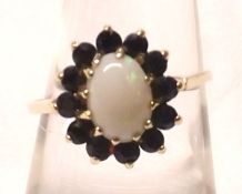 A hallmarked 9ct Gold Cluster Ring, featuring an oval Opal to the centre surrounded by small Dark