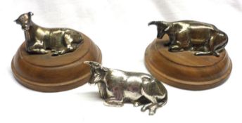 A group of three white metal Models of recumbent cows (two on plinth bases), largest 2 ½” long