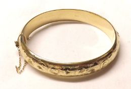 A hallmarked 9ct Gold Hollow Bangle, the hinged front engraved with floral and foliate design,