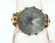 A yellow metal Dress Ring set with a large circular Aquamarine (worn and marks unclear)