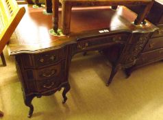 An early 20th Century American Walnut Desk, the top with gilt tooled red inset, the shaped front