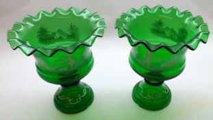 A pair of large Green Glass Pedestal Urns, decorated in white with Mary Gregory type design,