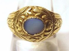 A precious metal Antique Gold Ring with carved detail and featuring an oval Moonstone to the centre