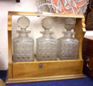 A 20th Century Three Bottle Tantalus, fitted with clear cut glass bottles, 12 ½” wide
