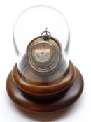 An early 20th Century Walnut and Glazed Watch Stand, the clear glass dome to a hinged mount and