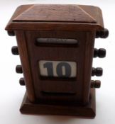 An early 20th Century Oak Cased Desk Calendar, the plinth-shaped case with glazed panels for day,
