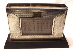 A George V Perpetual Desk Calendar of typical rectangular form, raised on an ebonised wooden base,