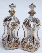 A pair of Clear Square Spirit Decanters of waisted form, decorated with applied gilt designs of