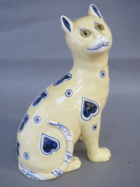 Yellow ceramic seated cat with blue heart decoration stamped 1896 to base, (a/f) 24 H