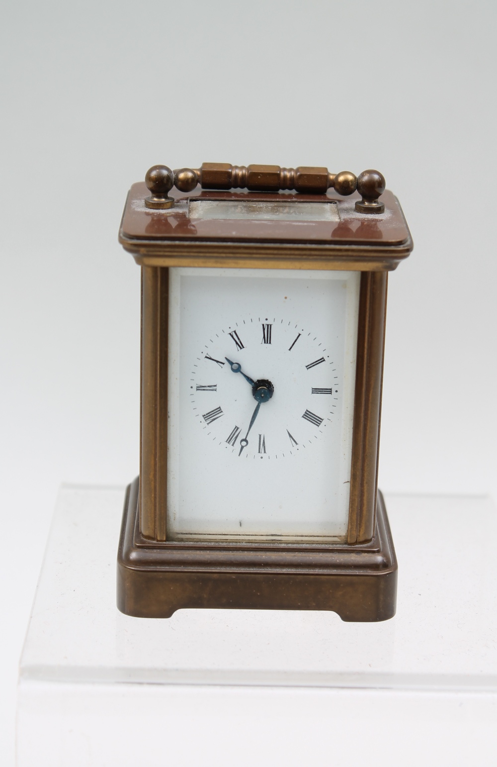A miniature brass carriage clock, enamel dial with Roman numerals.