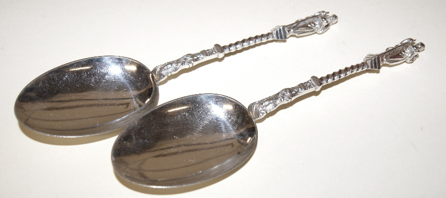 Good quality pair of silver-plated spoons, the grips with twist and repoussé detail, with an icon