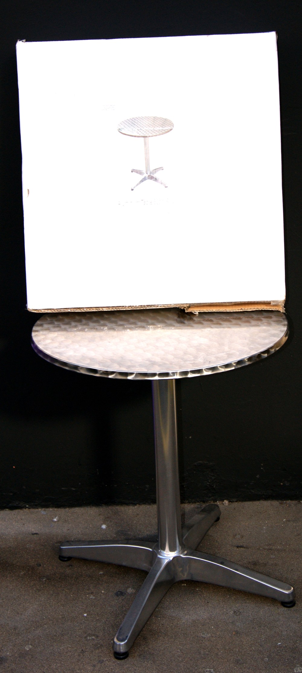 Aluminium circular table raised on a single pedestal base, together with another, boxed