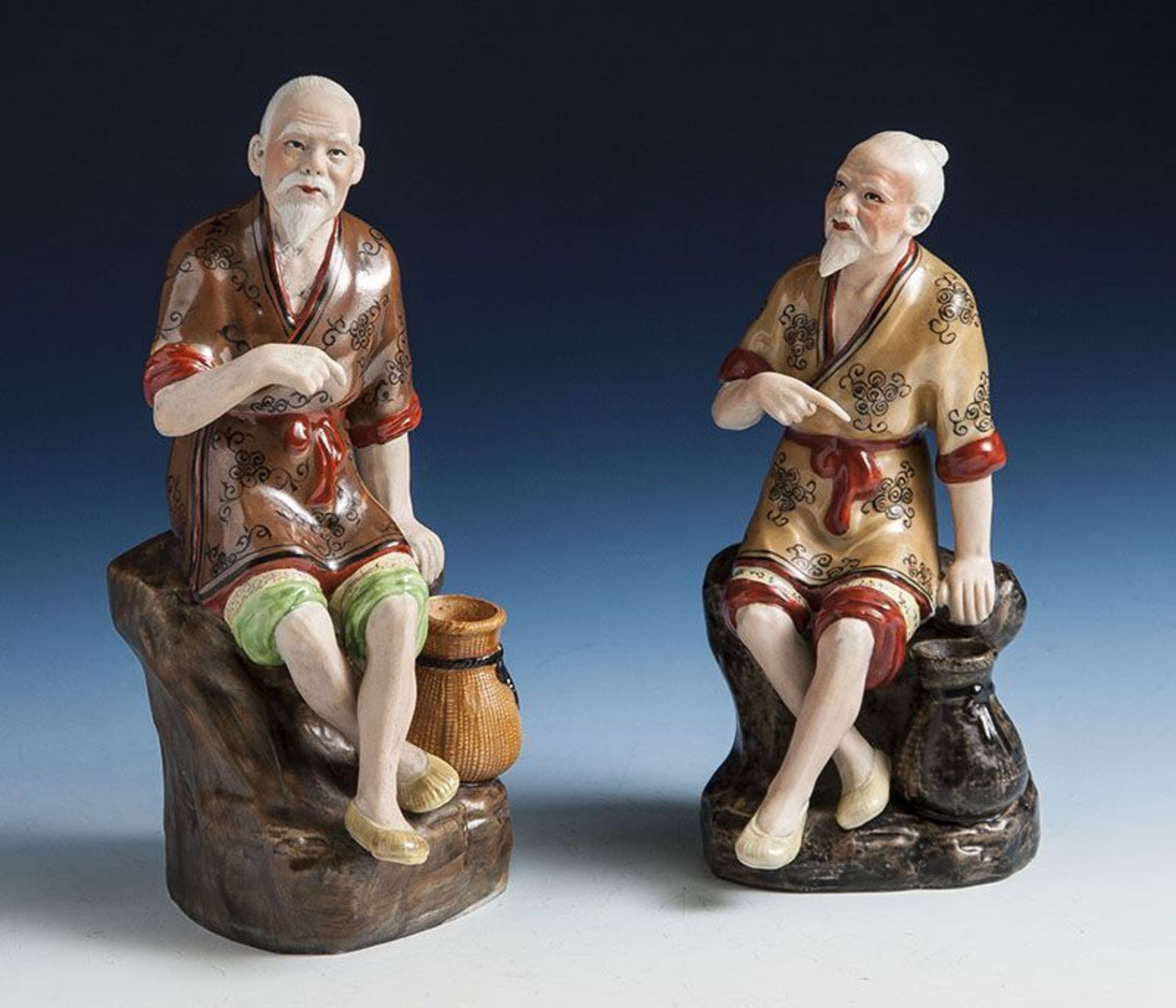 2 Porzellanfiguren, Japan, Meiji-Periode. Darstellung eines auf einem Stein sitzenden älteren Mannes
