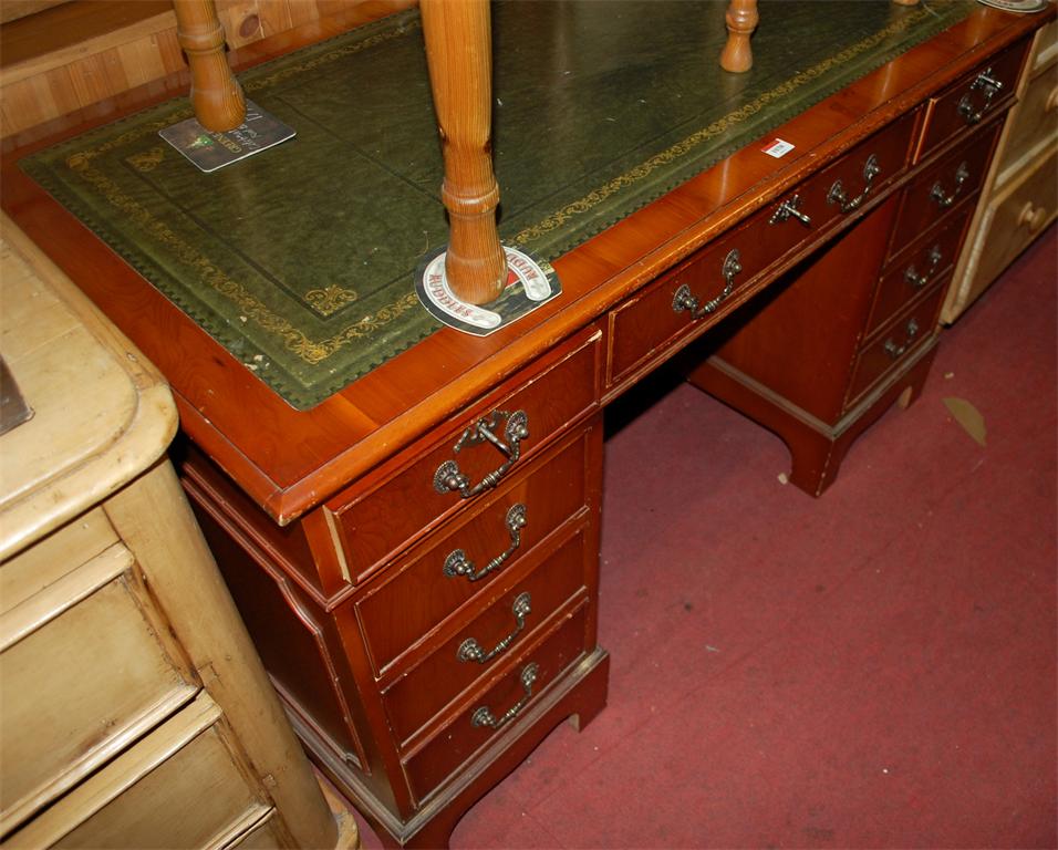 A reproduction yew wood and green leather gilt tooled inset twin pedestal writing desk