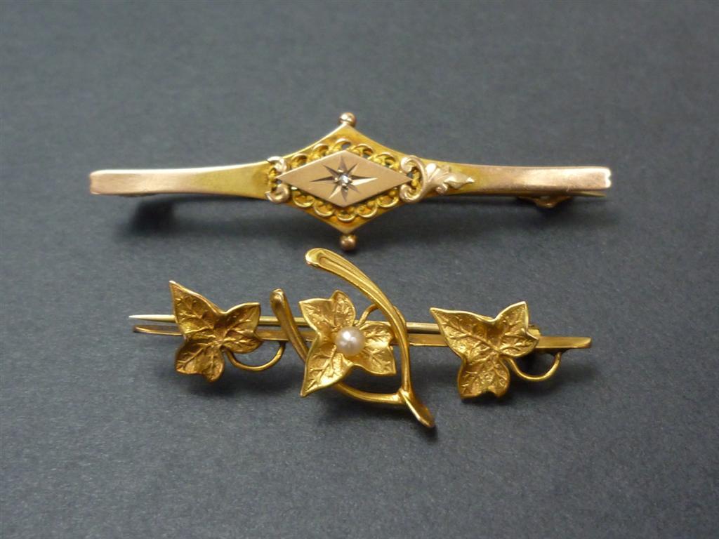 Two Victorian bar brooches, in 9ct and yellow metal, the former being Etruscan Revival in style,