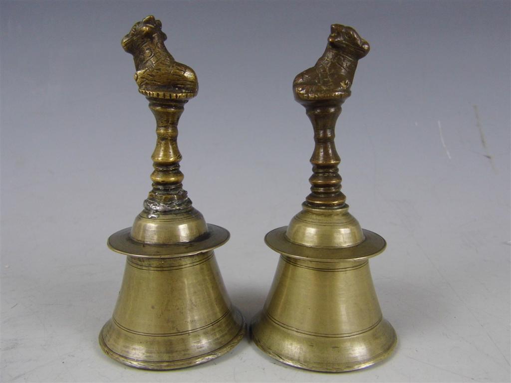 A pair of small Indian brass and cupro-nickel hand bells, their terminal modelled as the bull