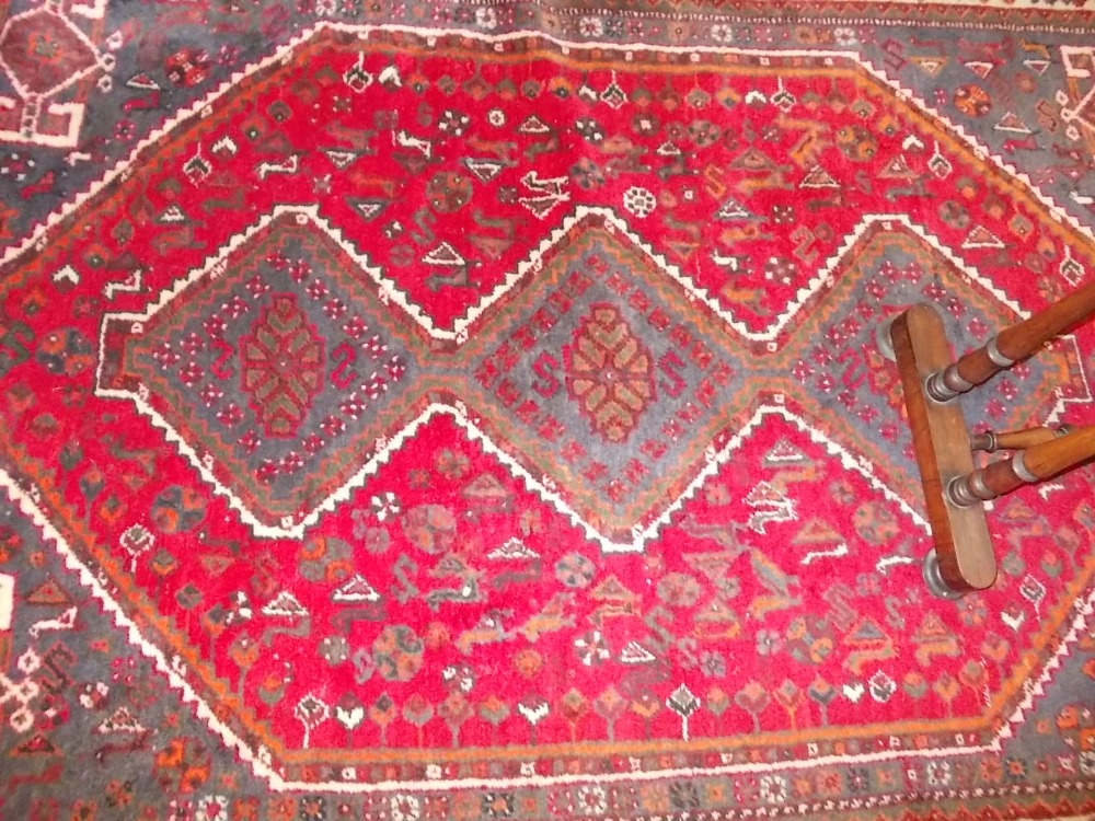 Shiraz rug with hooked medallion design on red ground with corner designs and borders (slight wear)