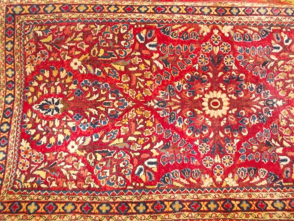 Small Sarouk rug with typical all-over floral design on a red ground with borders