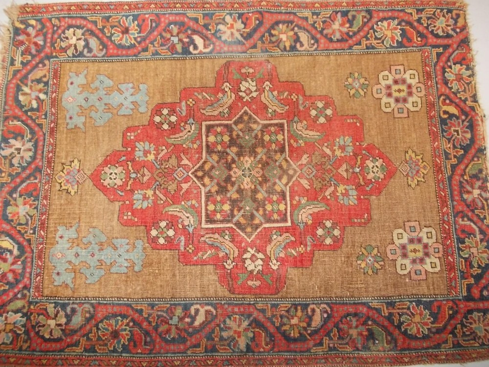 Small Kurdish rug with single medallion and flower head designs on a beige ground with meander