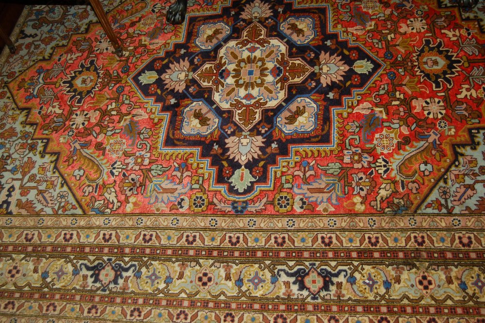 Modern Heriz carpet with medallion and all-over stylised floral design on a red ground with multiple