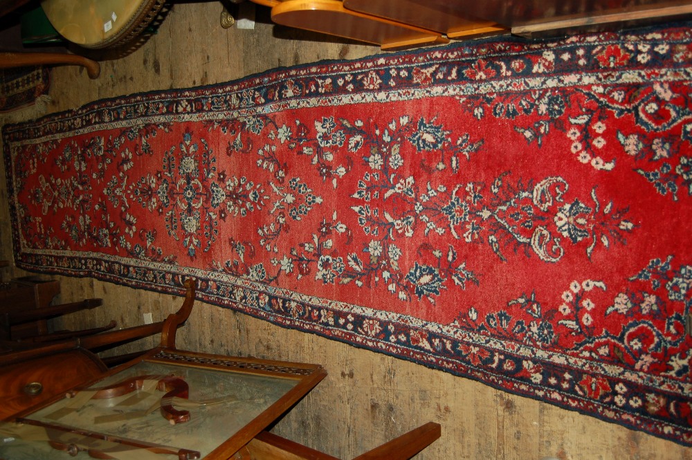 Sarouk runner with floral design on red ground with borders, 145ins x 33ins