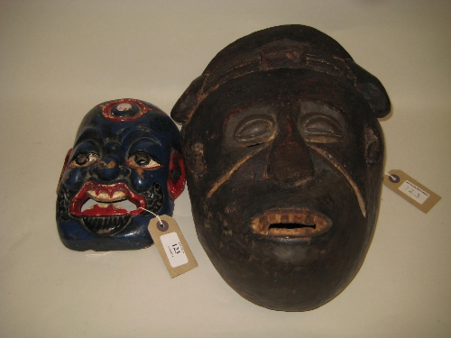 Blue and red painted carved wooden Buddhist mask, together with another carved wooden native mask