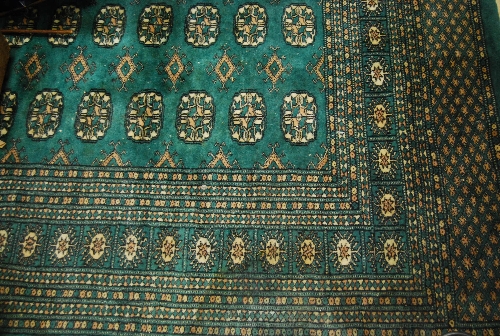 Pakistan Bokhara design carpet with multiple gols on a green ground, 9ft x 6ft 3ins