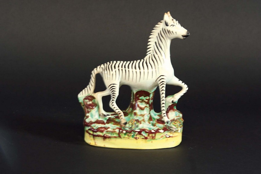 A STAFFORDSHIRE FIGURE OF A ZEBRA 6 1/2ins. (16.5cms.) highCondition reports are available via