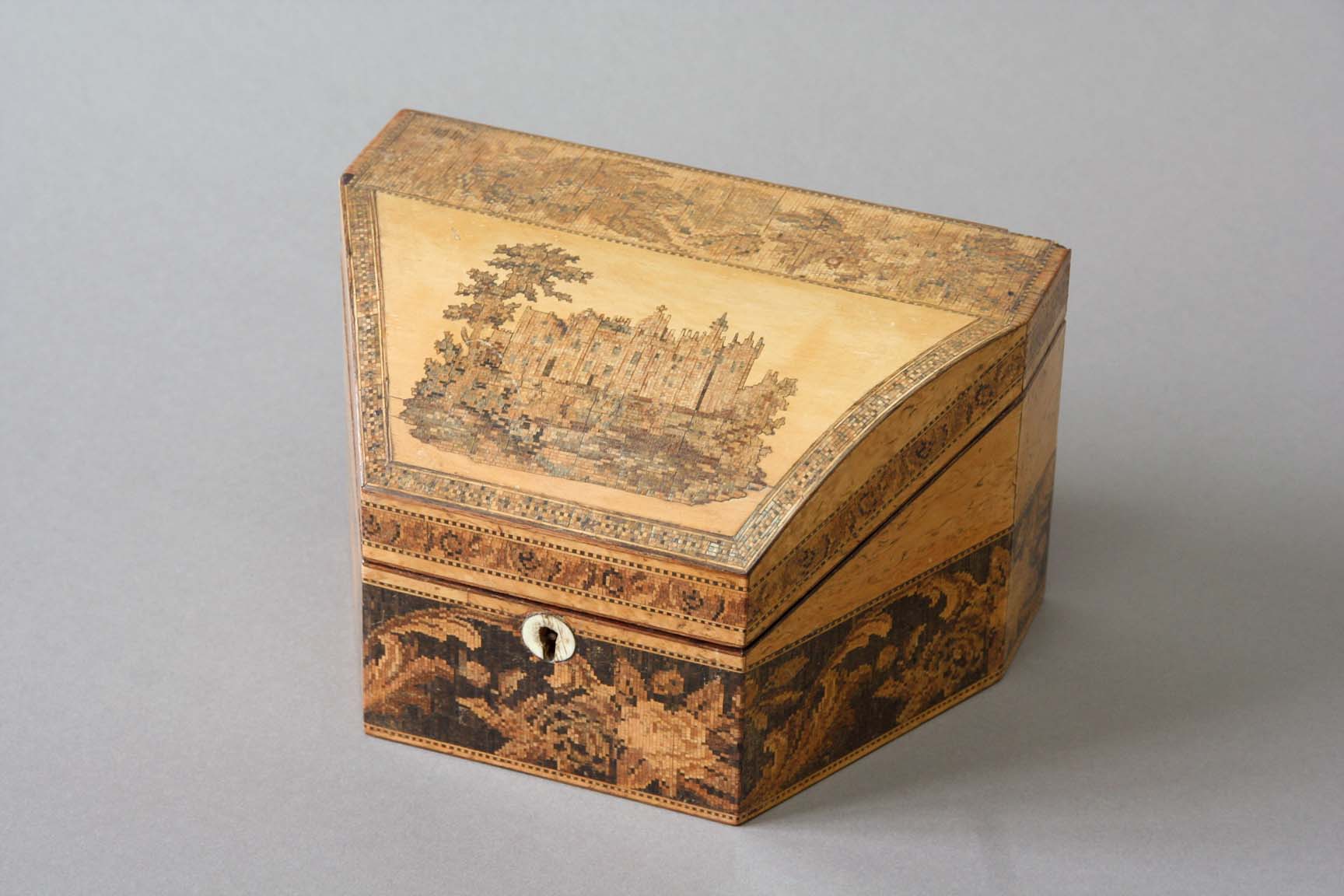 A TUNBRIDGE WARE STATIONERY BOX of wedge shape, the curved lid inlaid with a view of Warwick Castle,