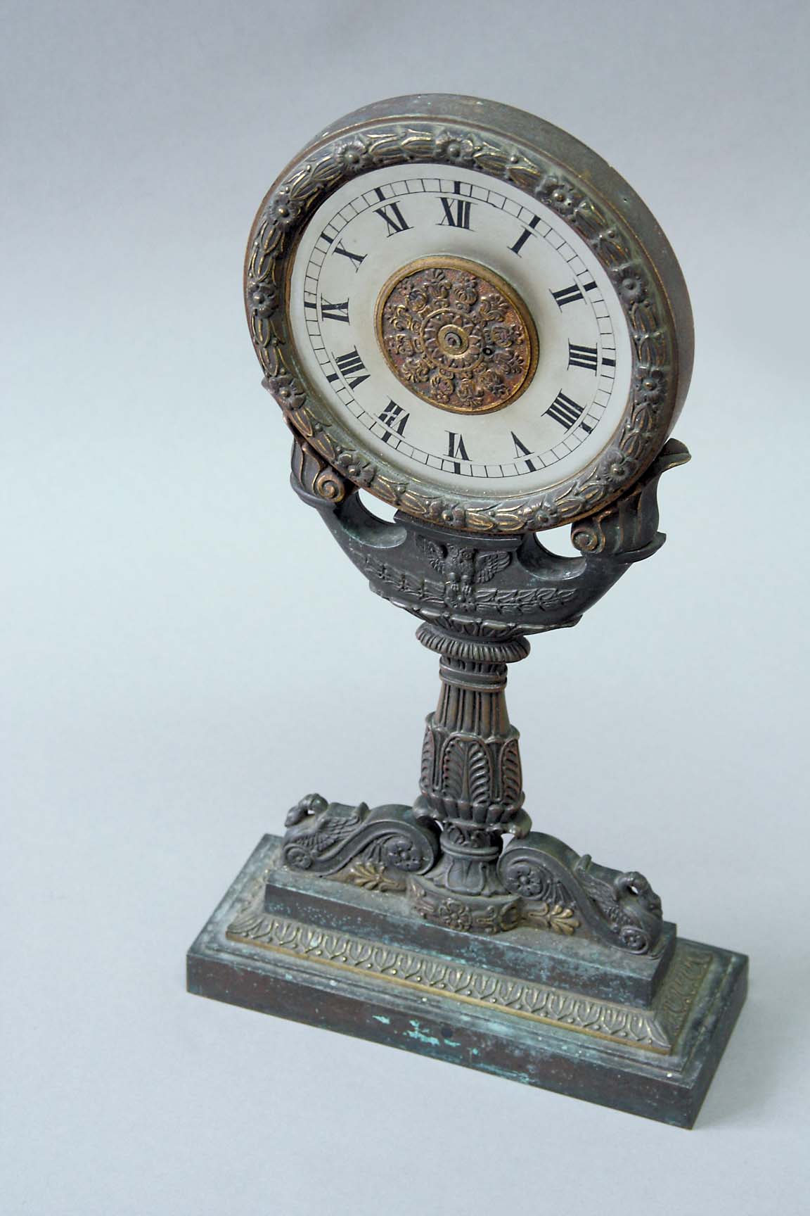 A BRONZE TABLE CLOCK dial frosted glass, movement watch, with foliate, engraved and pierced cock,