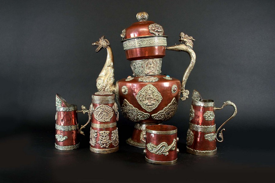 A TIBETAN COPPER AND BRASS CEREMONIAL TEA SERVICE each piece applied with cast plaques, the teapot