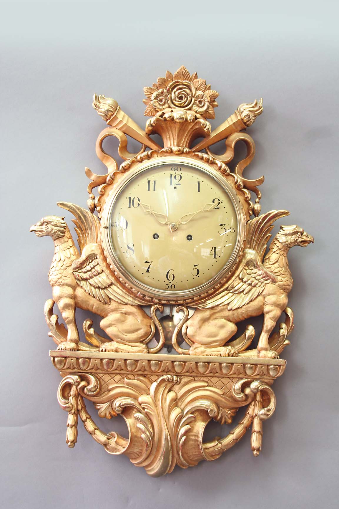 A SWEDISH GILTWOOD WALL CLOCK dial beige painted, case flanked by winged gryphons and surmounted