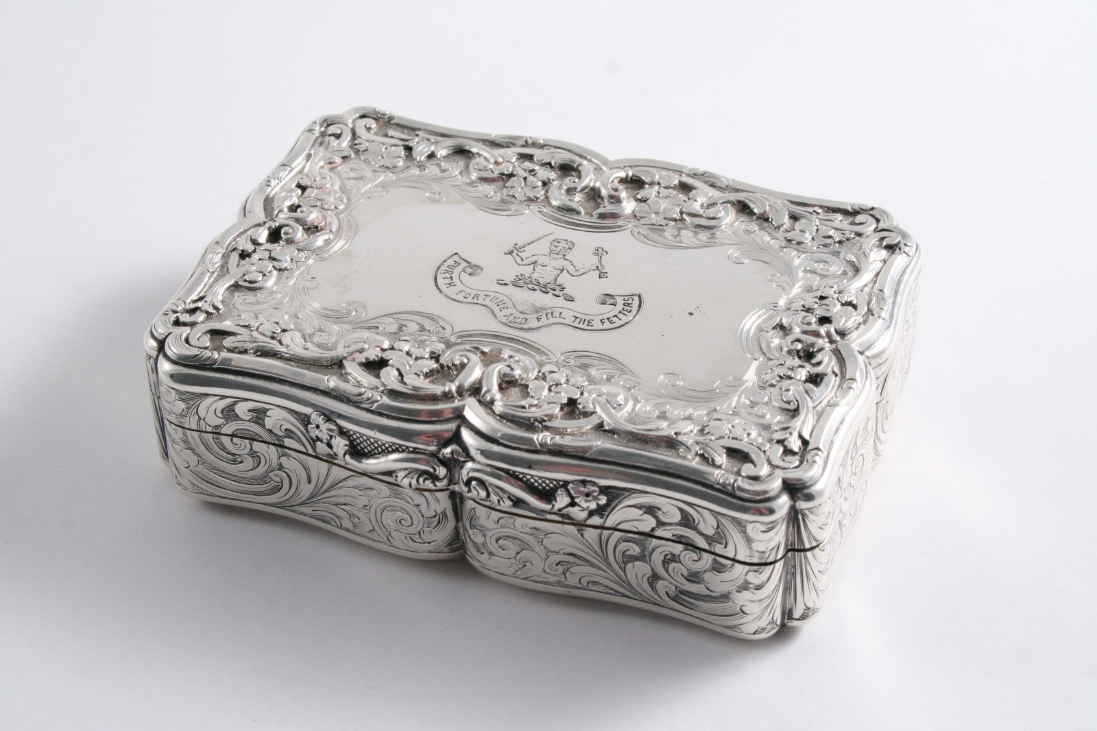 A VICTORIAN LARGE SNUFF BOX of oblong serpentine outline with floral scroll engraving, applied
