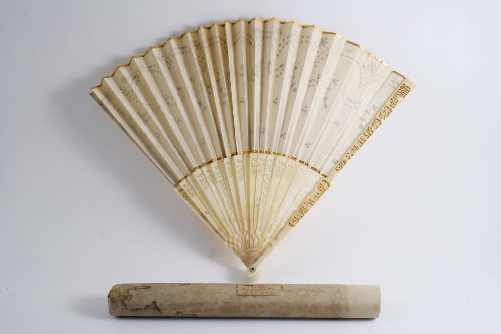 A 19TH CENTURY FAN with Chinese ivory sticks pierced & carved, the silk decorated with a pattern
