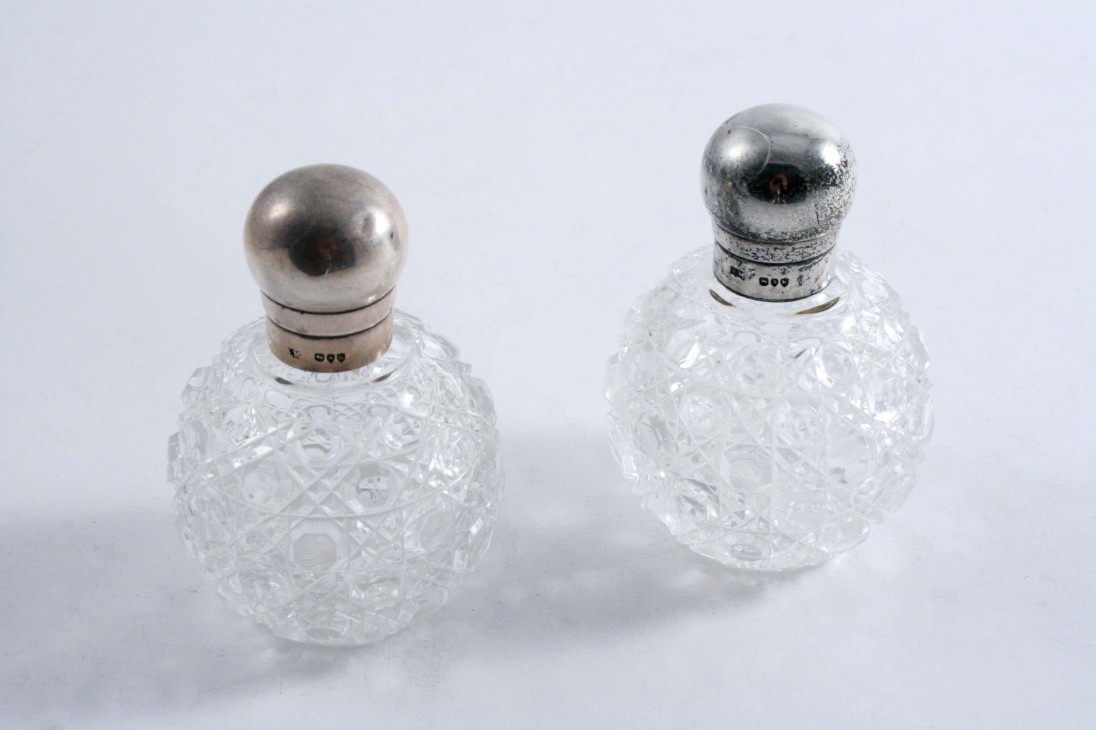 A PAIR OF VICTORIAN CUT GLASS MOUNTED SCENT BOTTLES with globular bodies & bulbous, screw caps, by