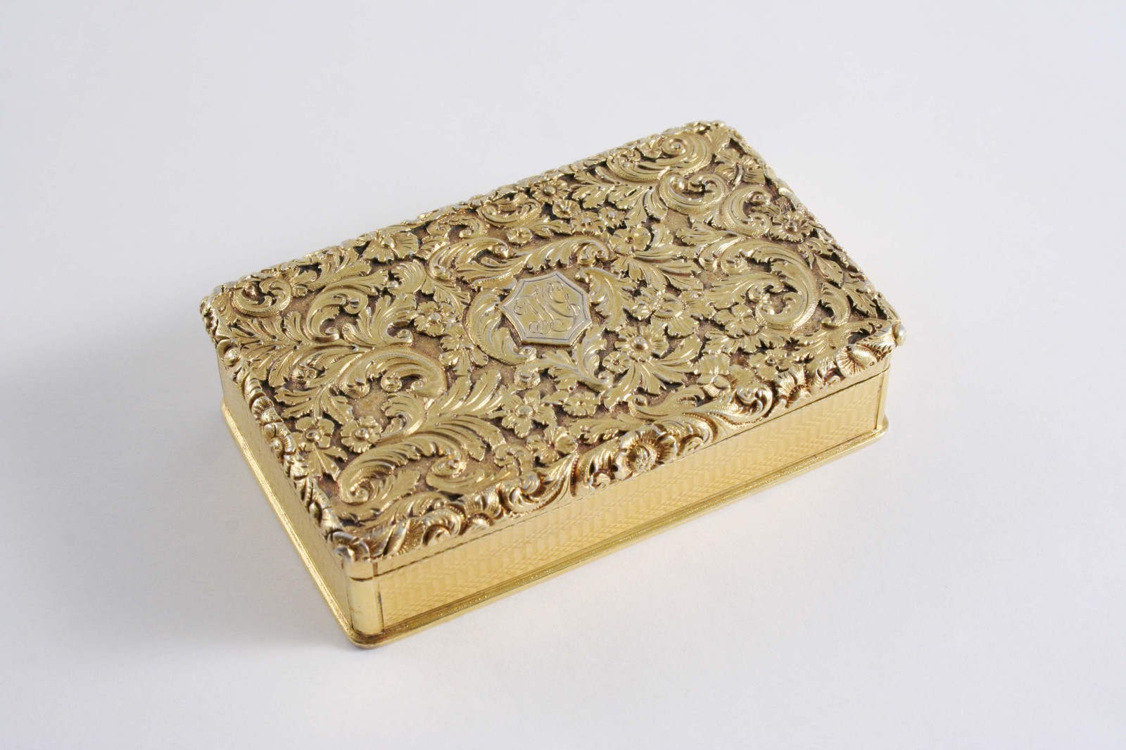 A GEORGE IV SILVERGILT OBLONG SNUFF BOX with engine-turned base & sides, the cover chased with