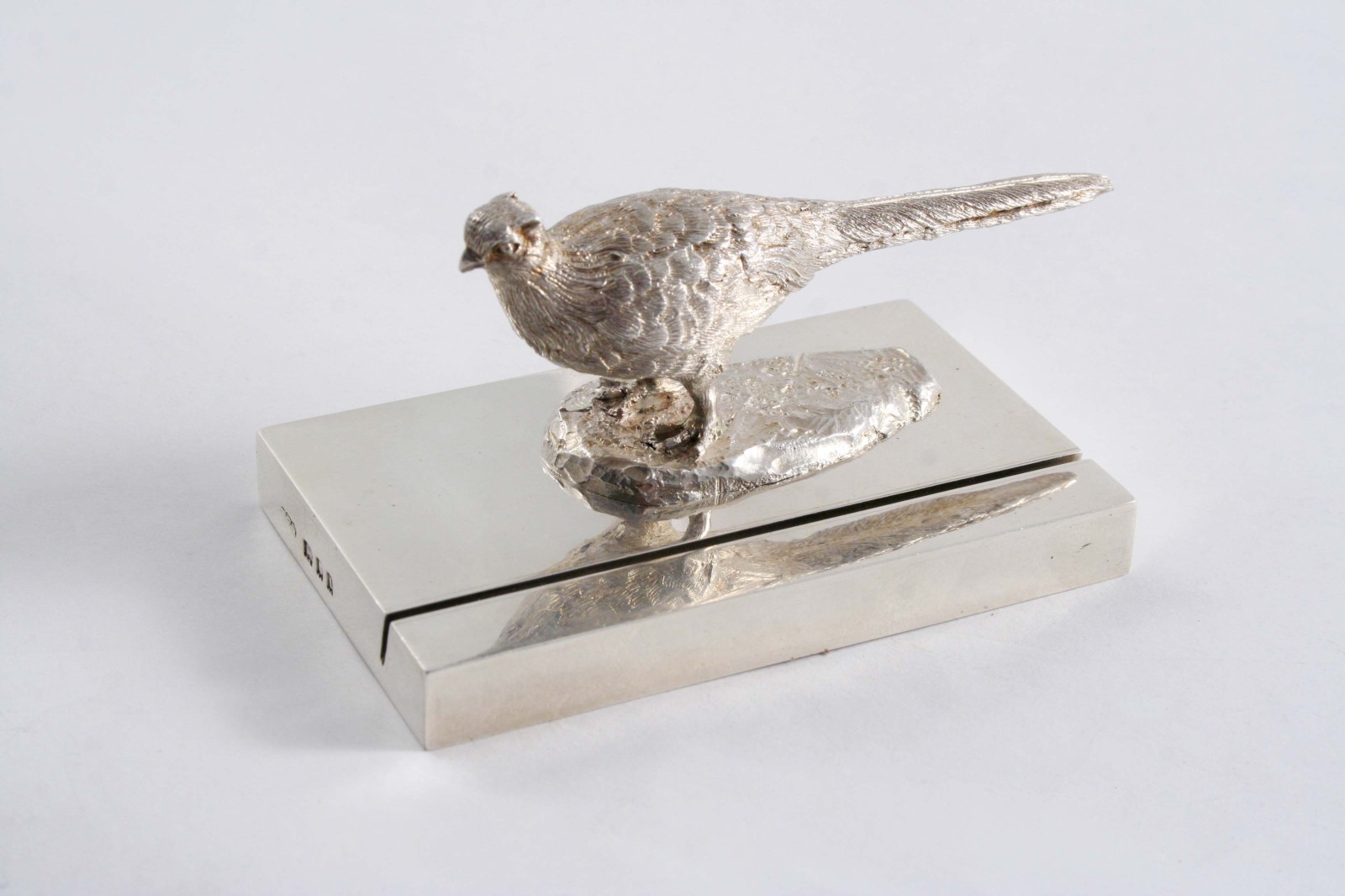 A MODERN CAST MENU HOLDER in the form of a cock pheasant on a plain oblong base, by W.F. Wright,