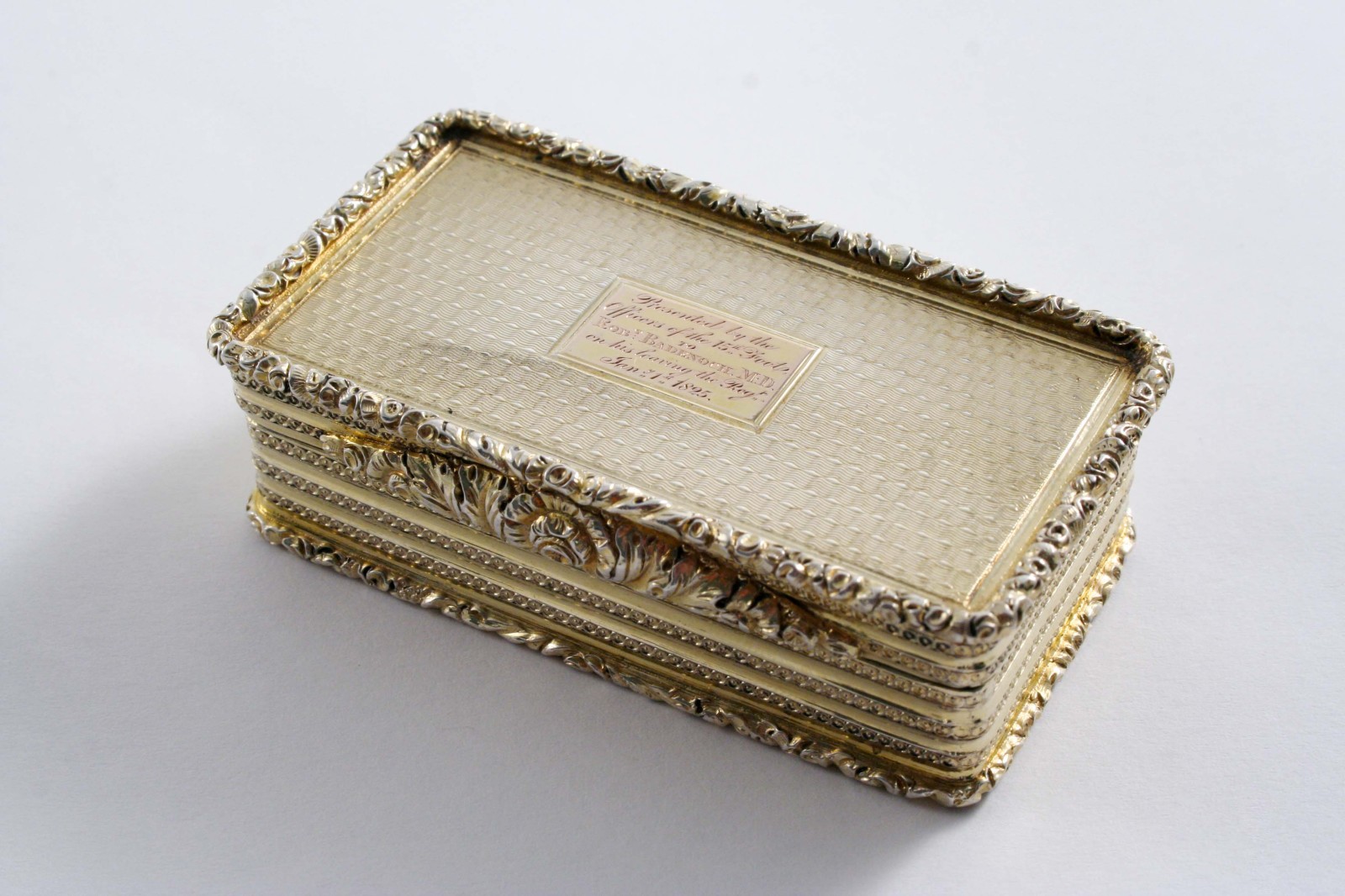 REGIMENTAL: A Victorian silvergilt oblong snuff box with engine-turned decoration, raised floral