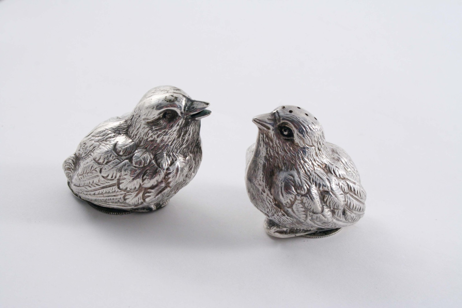 A PAIR OF EDWARDIAN NOVELTY CONDIMENTS (a salt & a pepper) in the form of fledgling chicks, with