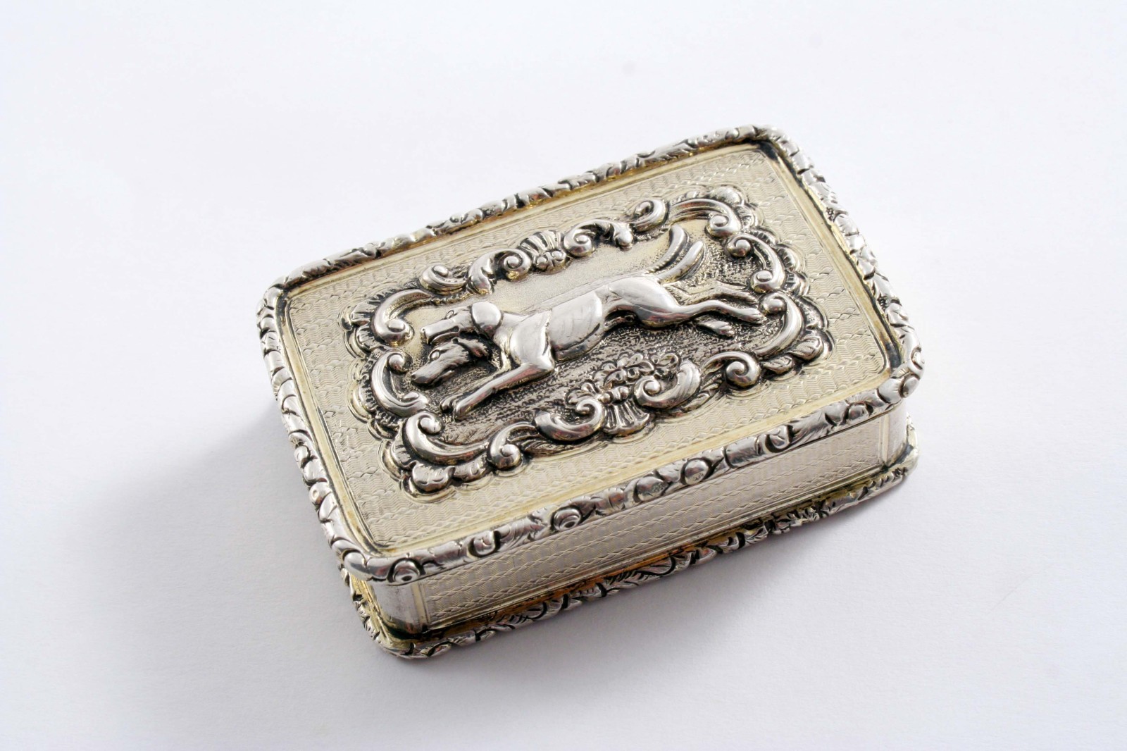 A GEORGE IV SILVERGILT SNUFF BOX of rounded oblong form with engine-turning, raised borders and an